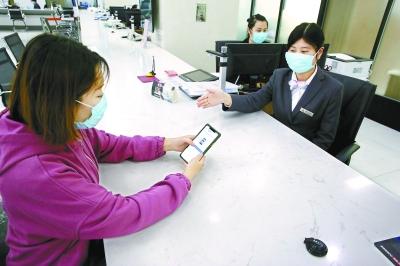  在東城區政務服務大廳，前來辦事的企業工作人員通過“北京通”授權電子證照應用